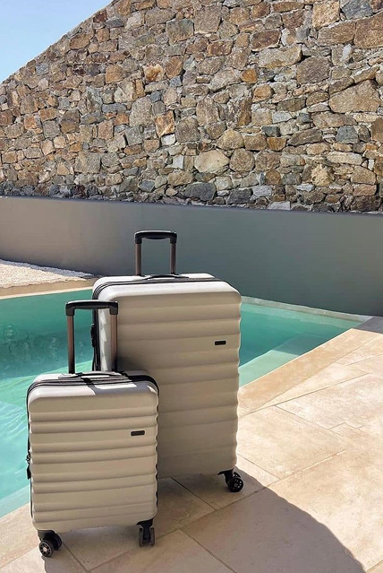 Silver hardshell luggage set beside a pool